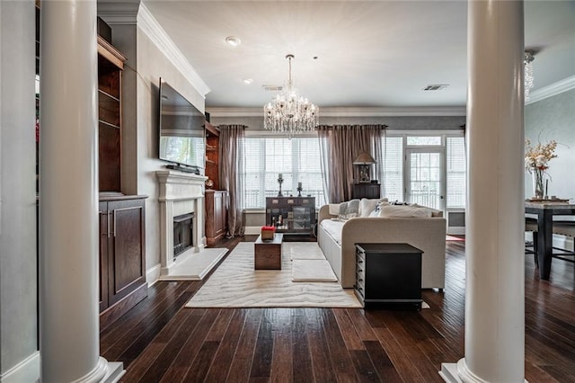 living area featuring visible vents, ornamental molding, decorative columns, dark wood-style floors, and a glass covered fireplace