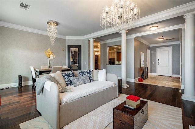 living area featuring hardwood / wood-style flooring, decorative columns, visible vents, and a chandelier