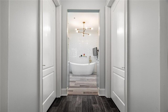 hallway featuring an inviting chandelier and dark wood-style flooring