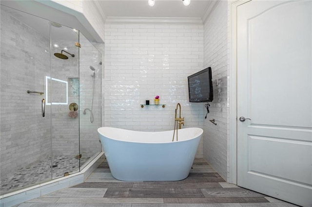 full bathroom with tile walls, a freestanding bath, a shower stall, and crown molding