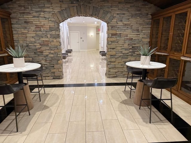 wine room featuring vaulted ceiling, crown molding, arched walkways, and wood tiled floor