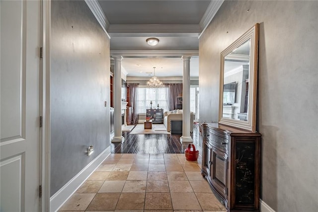 hallway featuring ornamental molding, an inviting chandelier, baseboards, and decorative columns