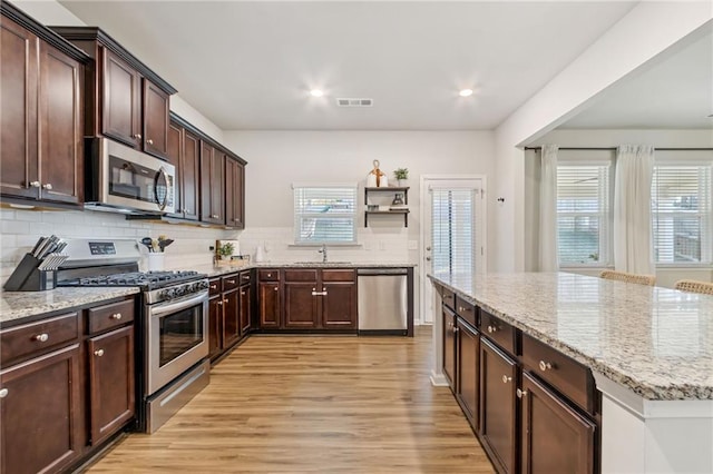 127 Ridgewood Way, Dallas, GA 30132 - kitchen featuring appliances with stainless steel finishes, a sink, light wood-type flooring, decorative backsplash, and dark brown cabinetry