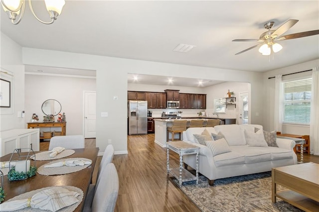 living room with ceiling fan with notable chandelier and wood-type flooring