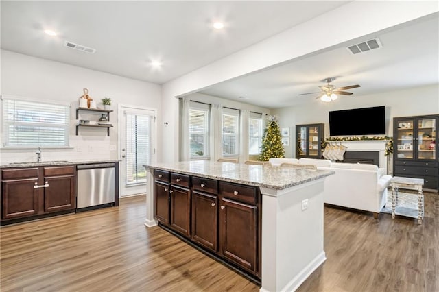 kitchen with hardwood / wood-style flooring, dark brown cabinetry, stainless steel dishwasher, a kitchen island, and sink