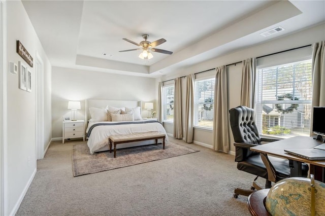 carpeted bedroom featuring ceiling fan and a raised ceiling