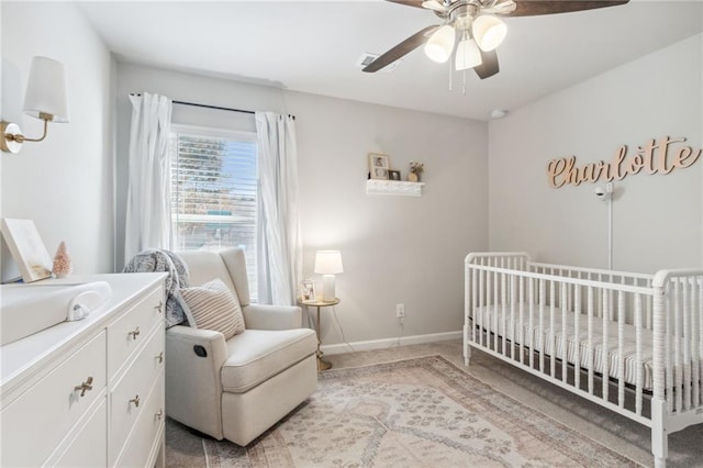 carpeted bedroom with ceiling fan and a crib