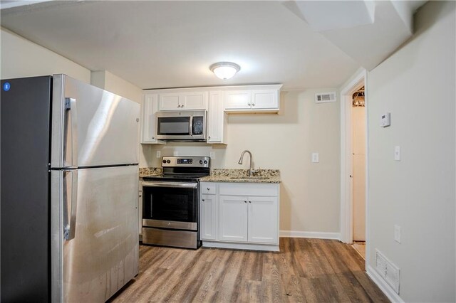 3743 Turner Heights Dr, Decatur, GA 30032 - kitchen with sink, stainless steel appliances, light stone counters, white cabinets, and light wood-type flooring