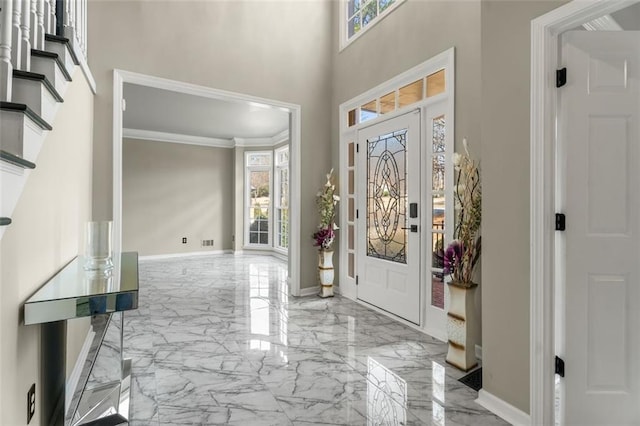 entryway with marble finish floor, a high ceiling, crown molding, and baseboards