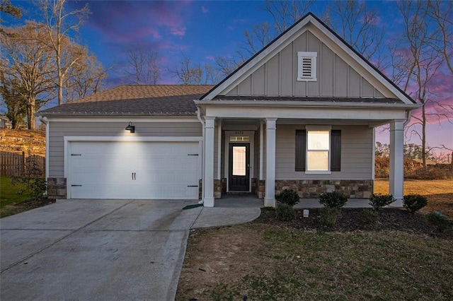 view of front of property featuring board and batten siding, an attached garage, covered porch, and stone siding