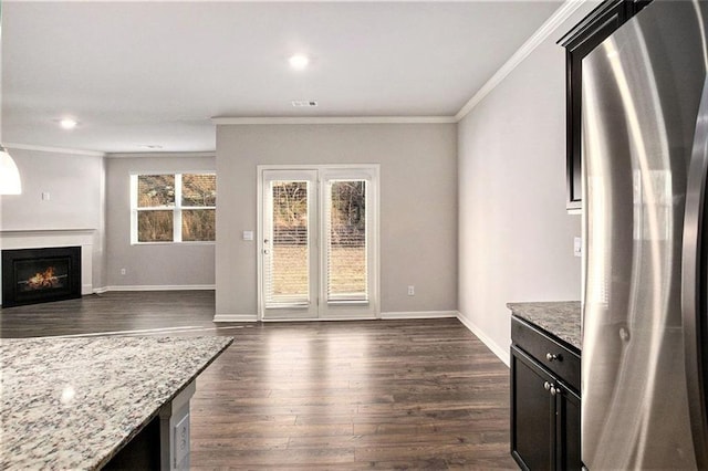 interior space featuring visible vents, dark wood-type flooring, a warm lit fireplace, crown molding, and baseboards