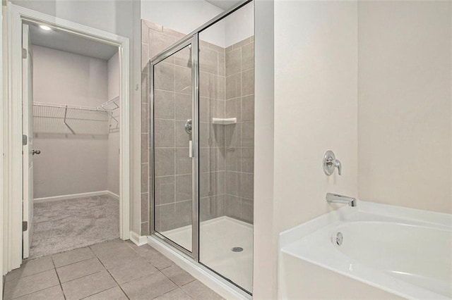 full bath featuring tile patterned flooring, a garden tub, a spacious closet, and a stall shower