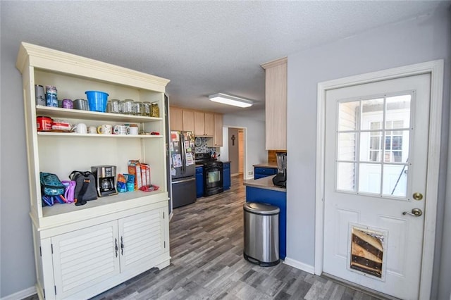 kitchen with freestanding refrigerator, gas stove, dark wood-style floors, a textured ceiling, and light brown cabinets