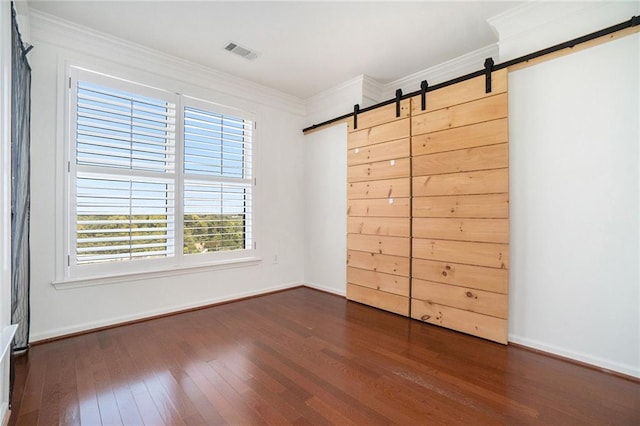 unfurnished bedroom featuring dark hardwood / wood-style floors, a barn door, and crown molding