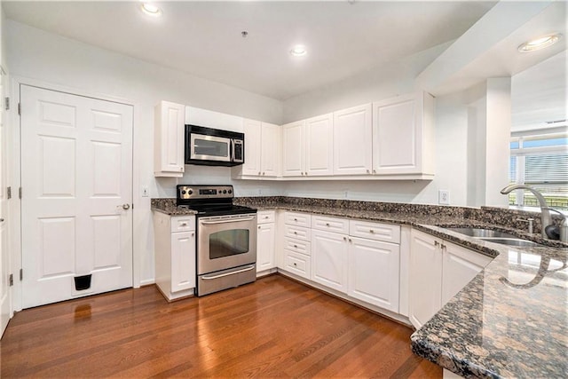 kitchen with dark hardwood / wood-style floors, white cabinetry, sink, and appliances with stainless steel finishes