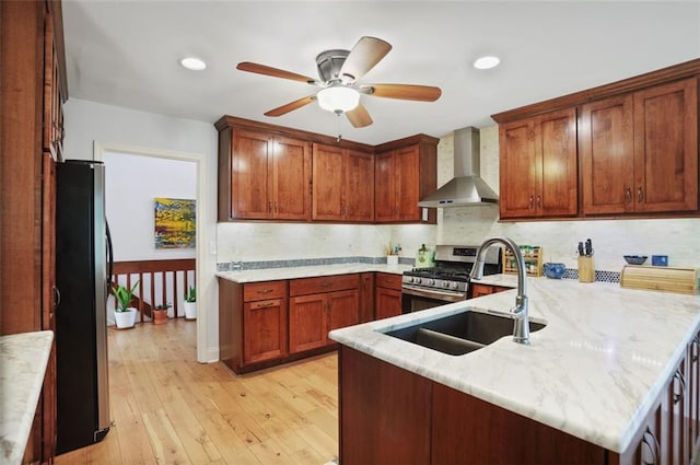 kitchen featuring sink, stainless steel appliances, kitchen peninsula, and wall chimney exhaust hood