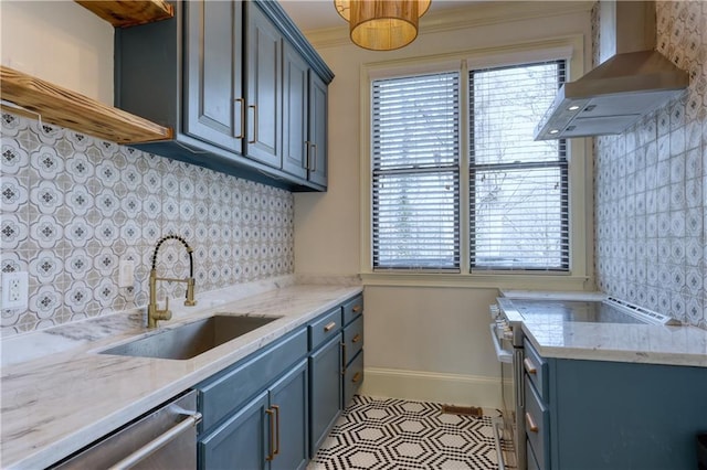 kitchen with a sink, ornamental molding, wall chimney range hood, blue cabinetry, and appliances with stainless steel finishes