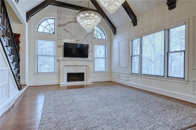 unfurnished living room with high vaulted ceiling, a fireplace, beamed ceiling, and wood finished floors