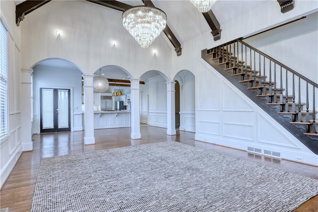 living area featuring visible vents, a decorative wall, beamed ceiling, and decorative columns