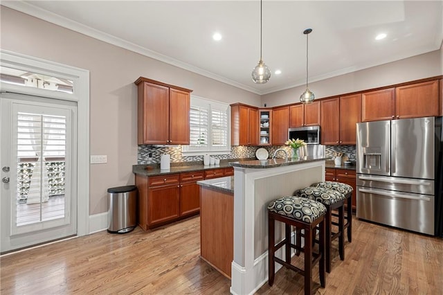 kitchen with a kitchen island, stainless steel appliances, light hardwood / wood-style flooring, and crown molding