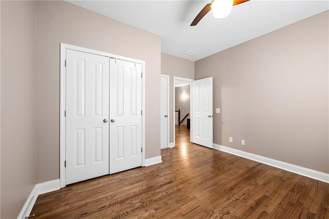 unfurnished bedroom with ceiling fan, dark hardwood / wood-style floors, and a closet