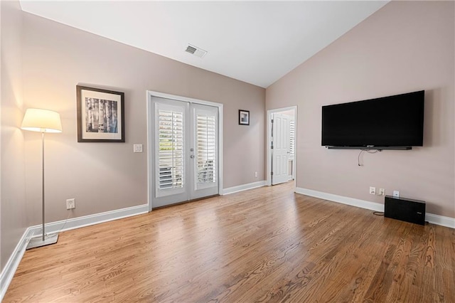 unfurnished living room featuring french doors, light hardwood / wood-style flooring, and lofted ceiling