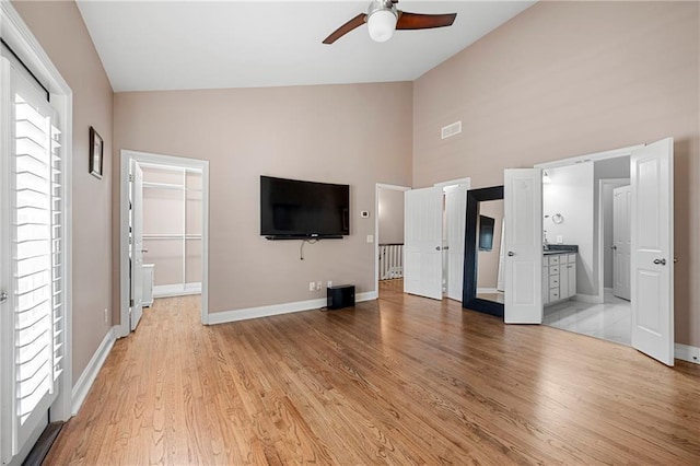 unfurnished bedroom with a walk in closet, ceiling fan, light hardwood / wood-style flooring, connected bathroom, and a closet