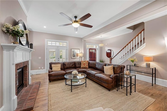 living room featuring a fireplace, light hardwood / wood-style flooring, ceiling fan, and ornamental molding