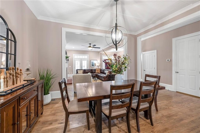 dining space featuring ceiling fan with notable chandelier, light hardwood / wood-style floors, and crown molding