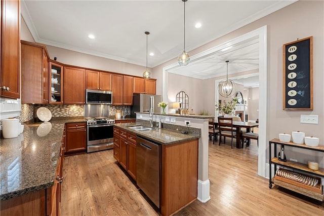 kitchen featuring light hardwood / wood-style floors, dark stone countertops, pendant lighting, and appliances with stainless steel finishes