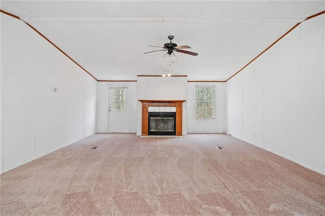 unfurnished living room featuring a tile fireplace, a healthy amount of sunlight, light carpet, and vaulted ceiling