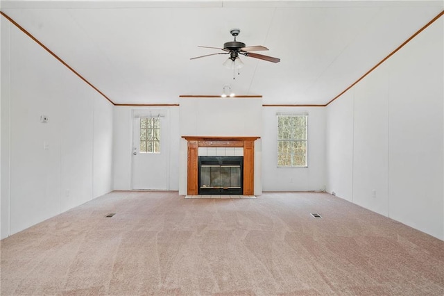 unfurnished living room with light carpet, a tile fireplace, a ceiling fan, and crown molding