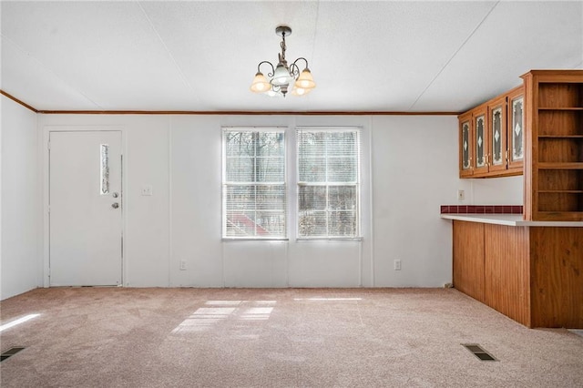 unfurnished dining area with ornamental molding, light colored carpet, and visible vents