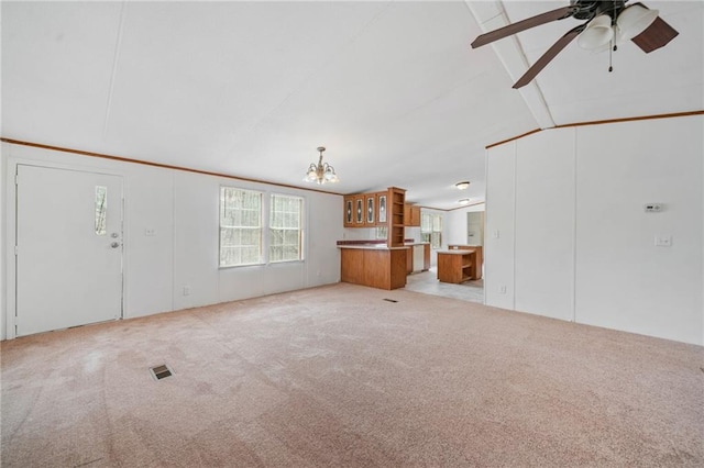 unfurnished living room with vaulted ceiling with beams, ceiling fan with notable chandelier, visible vents, and light colored carpet