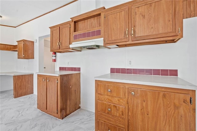 kitchen featuring brown cabinets, marble finish floor, light countertops, and under cabinet range hood