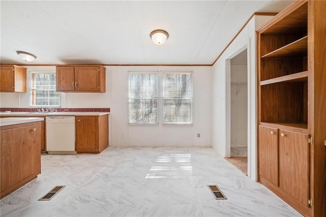 kitchen featuring light countertops, brown cabinetry, white dishwasher, and visible vents