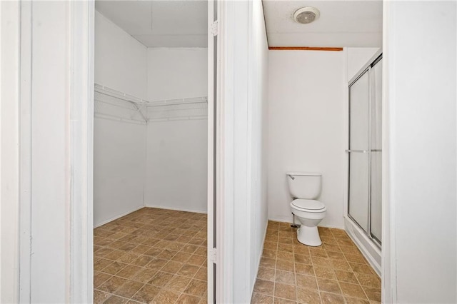 full bathroom with toilet, a stall shower, and a walk in closet