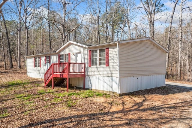 view of front of home with a wooden deck, dirt driveway, and stairs