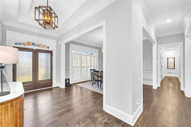 foyer entrance featuring a chandelier, french doors, crown molding, and dark wood finished floors