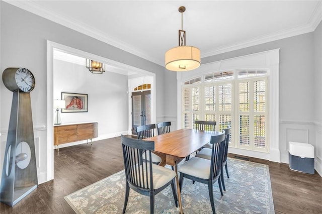 dining space with a decorative wall, a wainscoted wall, wood finished floors, french doors, and ornamental molding