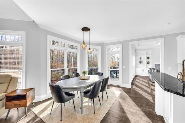 dining room featuring built in features, crown molding, baseboards, and dark wood-style floors