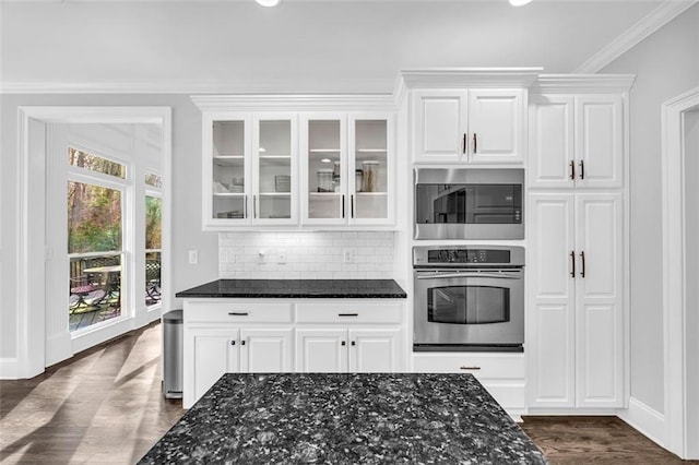 kitchen with dark wood-type flooring, dark stone countertops, and oven