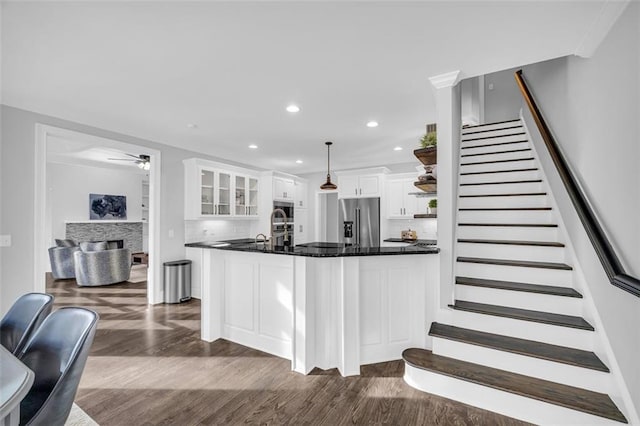 kitchen with dark wood-style floors, glass insert cabinets, appliances with stainless steel finishes, a fireplace, and white cabinetry