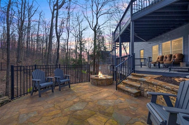 view of patio with a fire pit, a deck, and fence