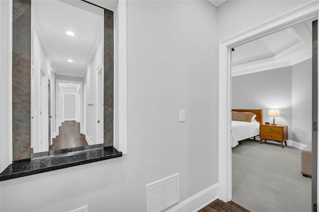 hall with carpet flooring, visible vents, crown molding, and baseboards