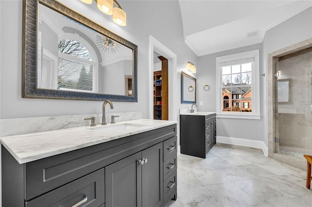 bathroom featuring a stall shower, two vanities, a sink, and baseboards