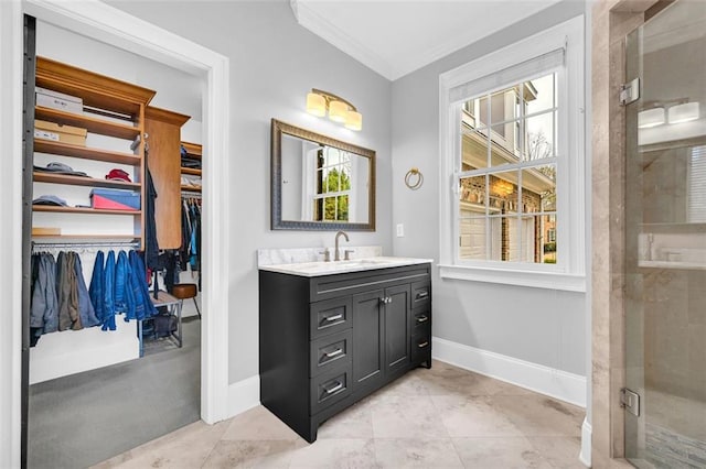 bathroom with a spacious closet, ornamental molding, a healthy amount of sunlight, vanity, and baseboards