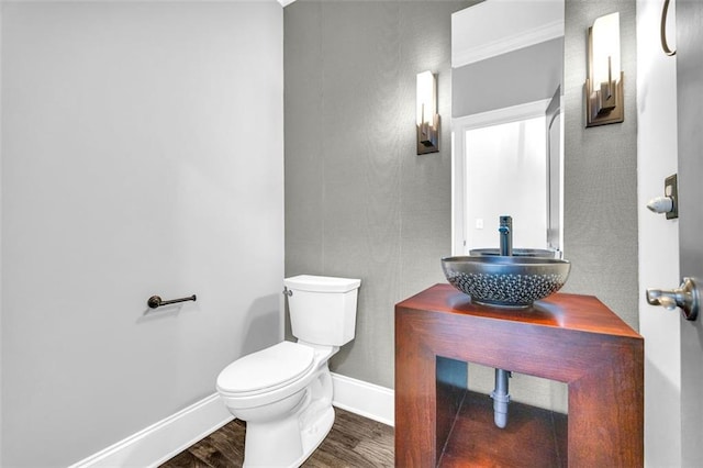 bathroom with toilet, baseboards, a sink, and wood finished floors