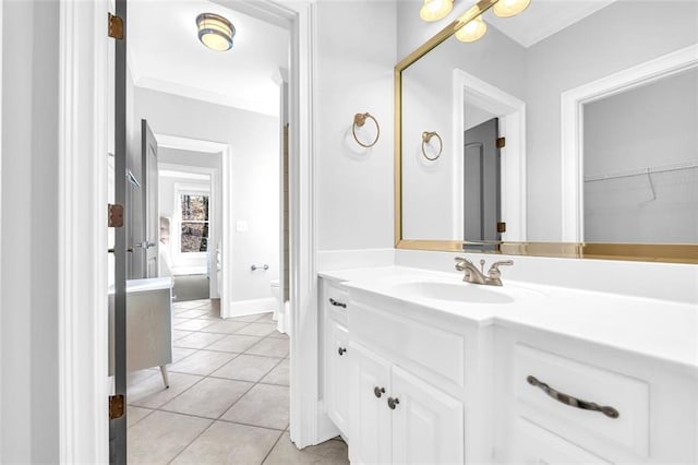 bathroom with crown molding, toilet, vanity, baseboards, and tile patterned floors