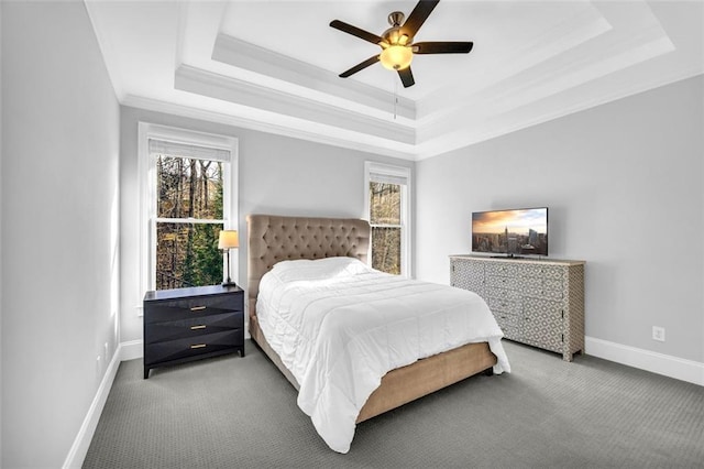 carpeted bedroom with multiple windows, a raised ceiling, and baseboards